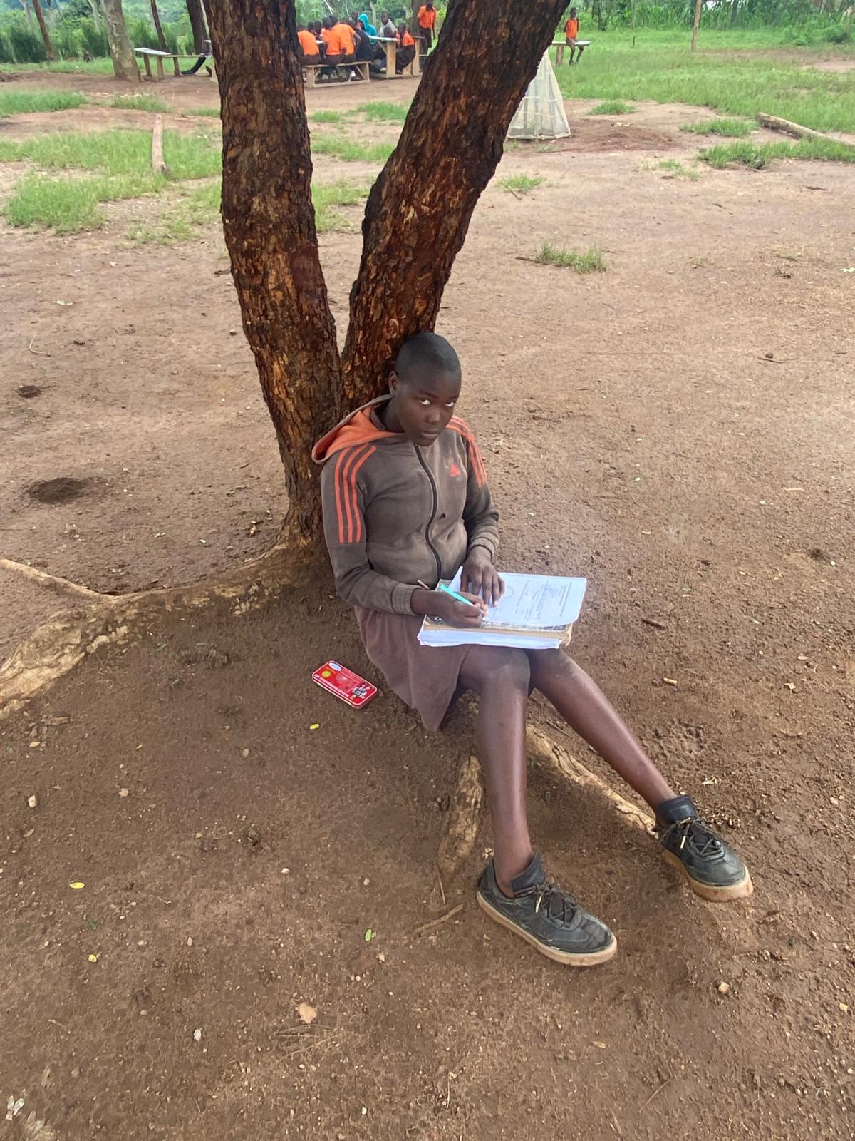 Teacher conducting an outdoor classroom lesson under a tree at Mission Destiny